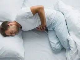 Man in bed with stomach pain