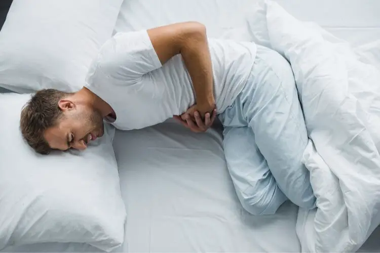 Man in bed with stomach pain
