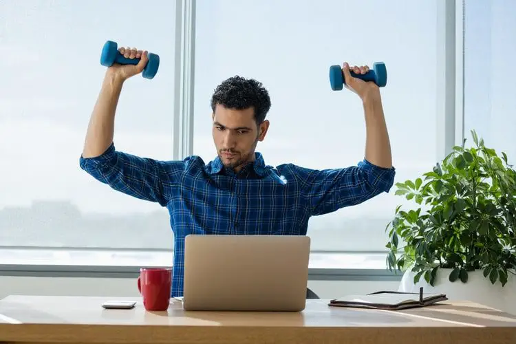Man using dumbbells while working in office