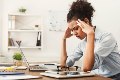 Woman with a headache at work holding her head in pain